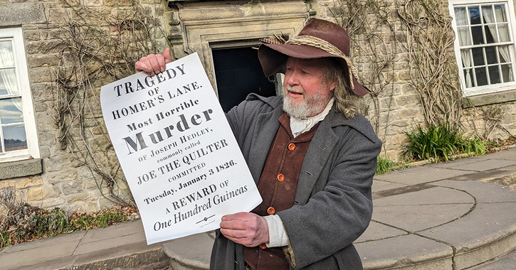 man in Georgian costume holds up poster about murder of Joe the Quilter at Beamsih Museum